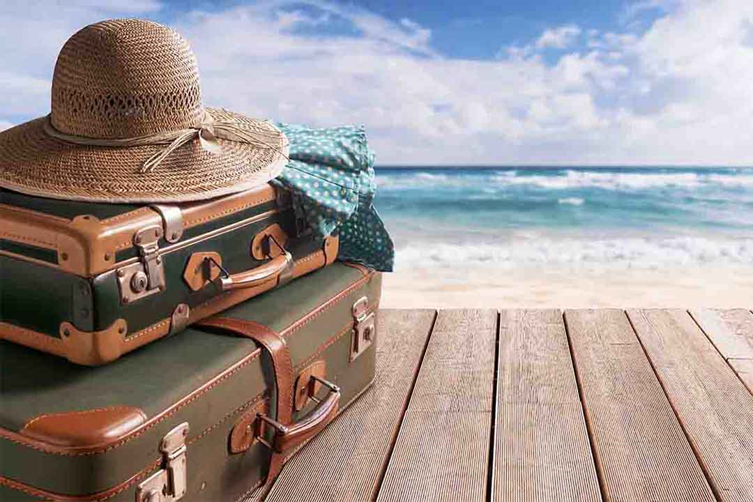 Zwei Kopper mit einem Hut liegen auf einem Steg vor dem Meer