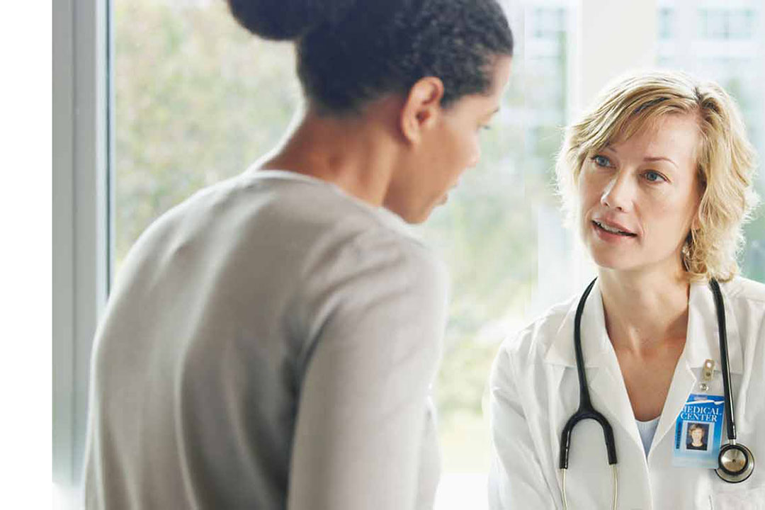 Ärztin mit Stethoskop berät eine junge Patientin