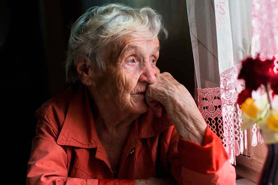 Alte einsame Frau sitzt am Fenster