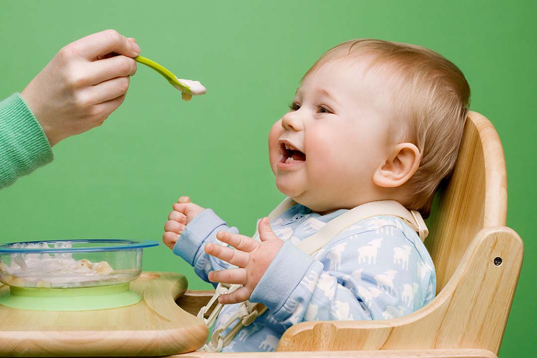 Baby im Hochstuhl wird gefüttert