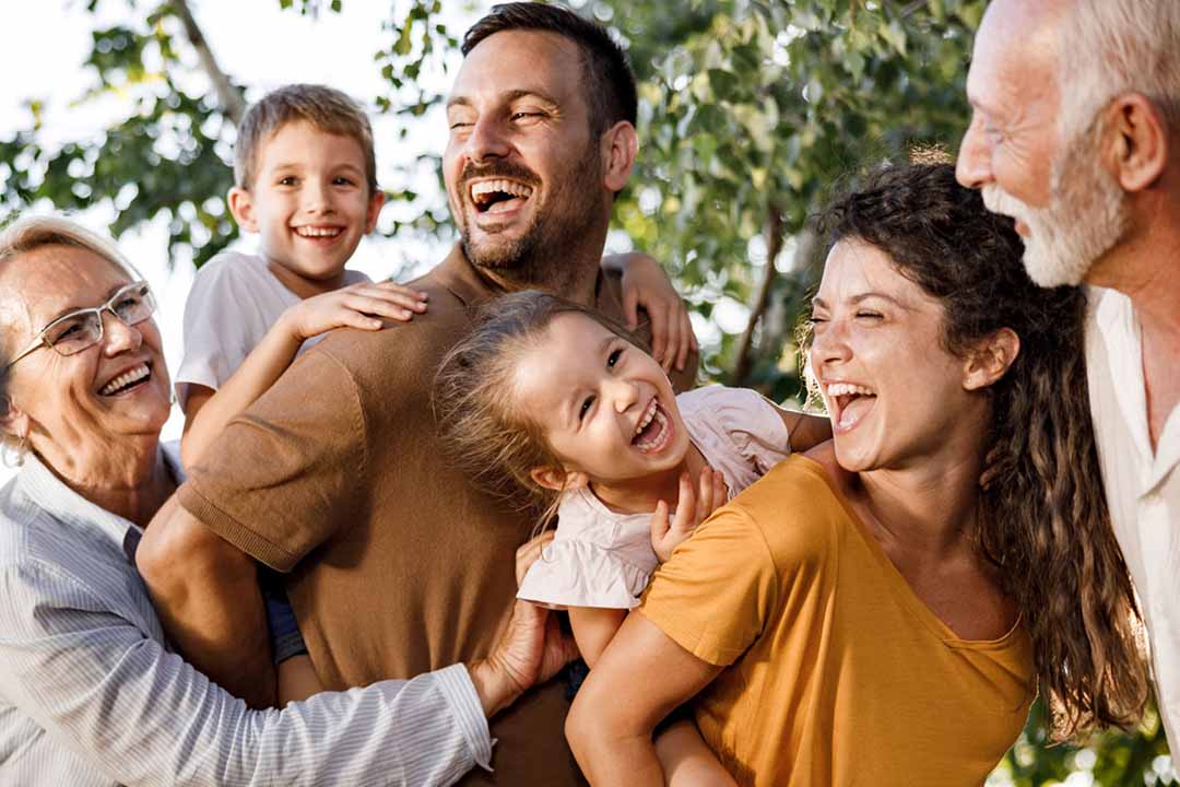 Eine Familie mit 6 lachenden Personen vor einem Baum