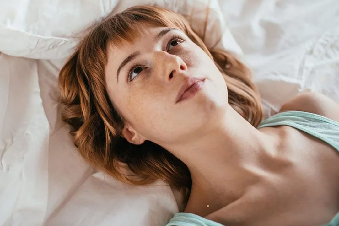Eine Frau liegt im Bett und schaut zur Decke