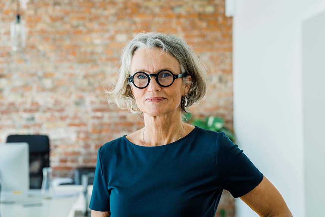 Frau mit Brille steht im Büro