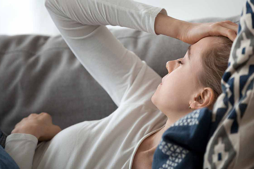 Eine Frau mit Herzmuskelentzündung liegt erschöpft auf dem Sofa