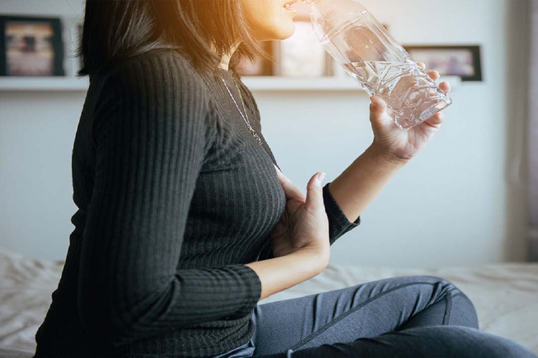 Frau mit Wasserflasche und Sodbrennen