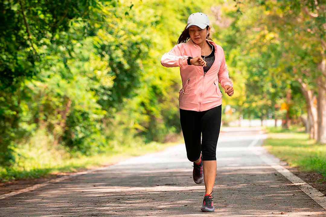 Frau schaut beim Joggen auf die Uhr