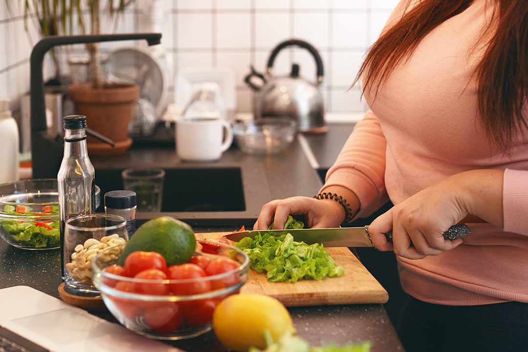 Frau schneidet Gemüse in der Küche