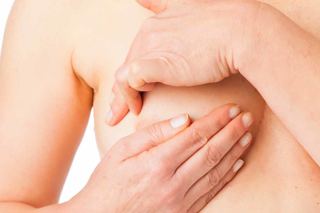 Frau tastet ihre Brust nach Knötchen ab