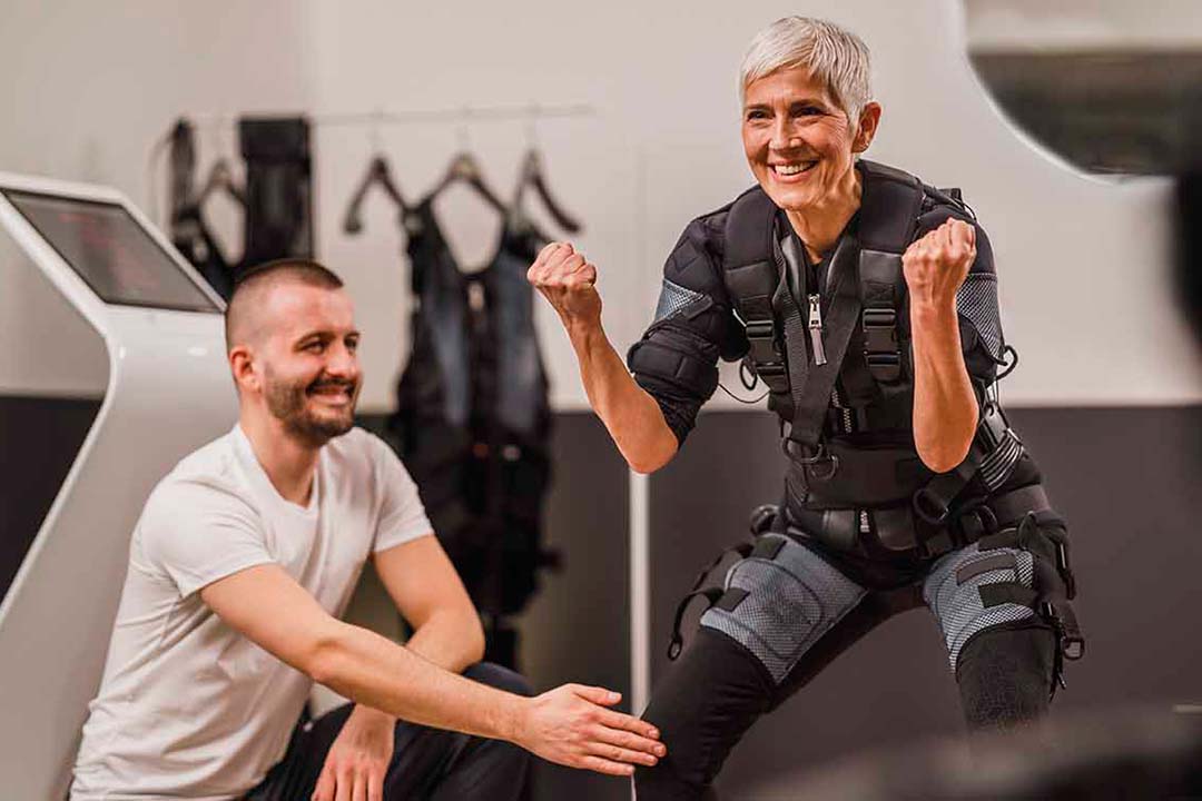 Frau trainiert in der Hocke mit einem Trainer die Muskulatur