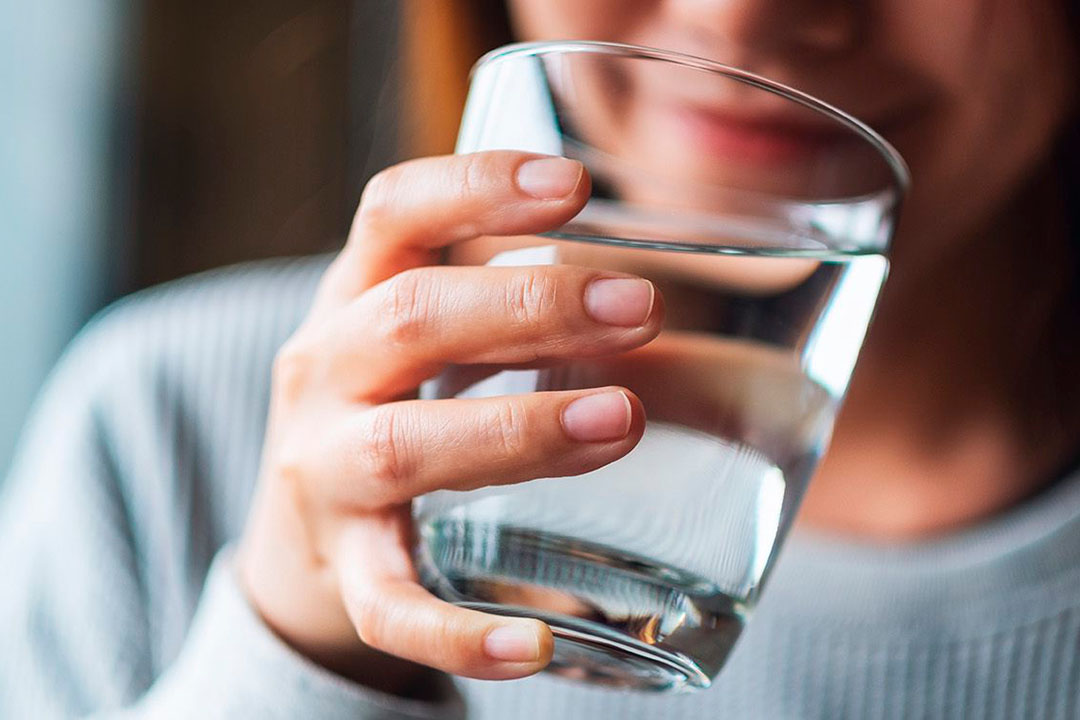 Frau trinkt Wasser aus einem Glas