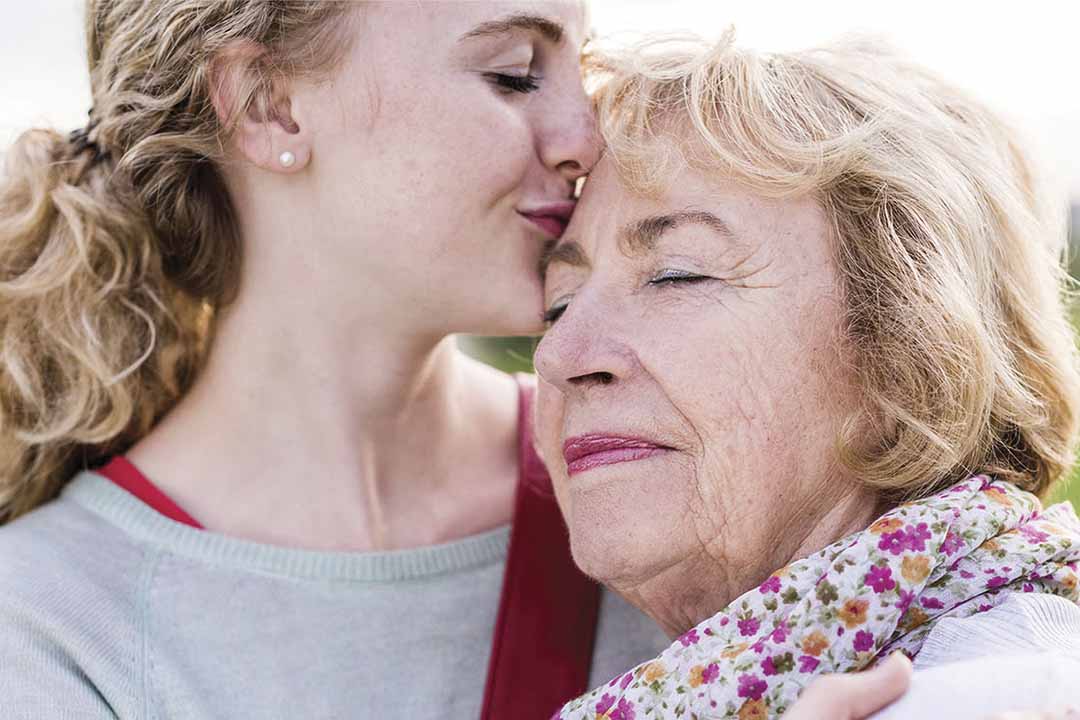 Junge Frau nimmt Seniorin in den Arm