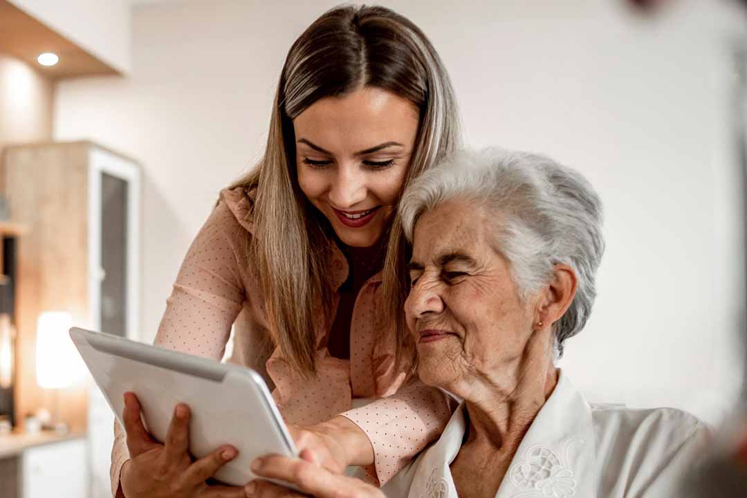 Junge Frau zeigt älterer Frau ein Tablet