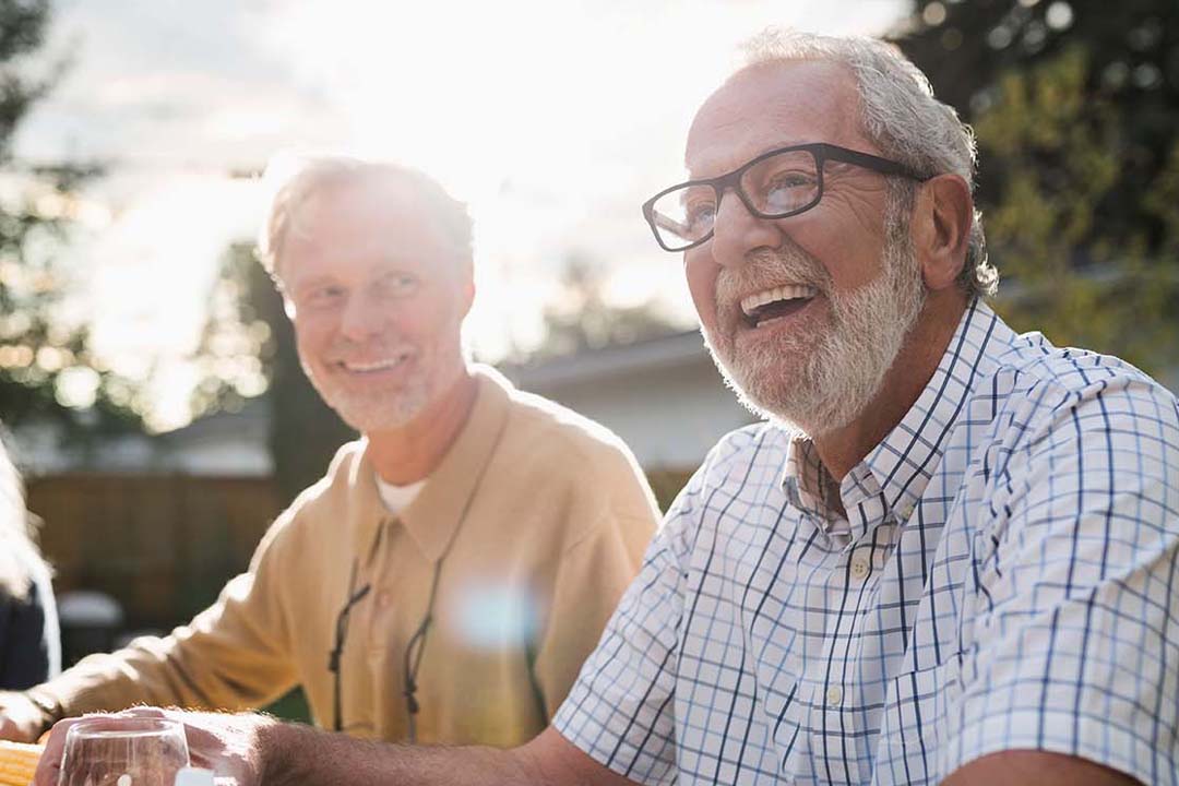 Lächelnde Senioren an einem gedeckten Gartentisch
