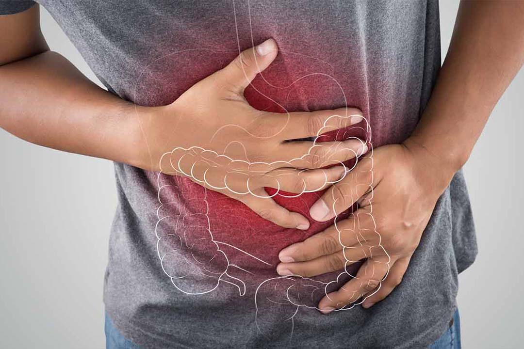 Mann hält sich Haende auf rote Stelle am Bauch