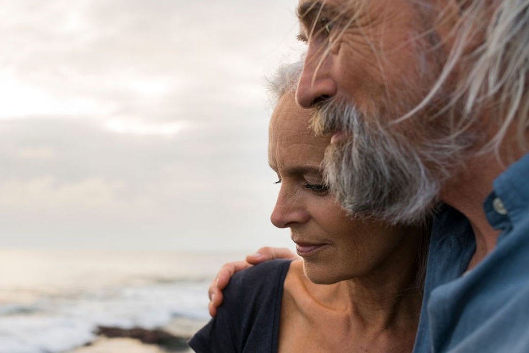 Mann und Frau stehen am Meer und schauen in die Ferne