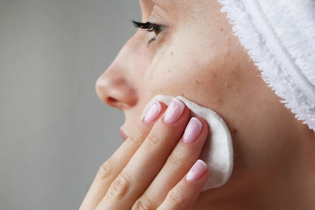 Frau reinigt ihr Gesicht mit einem Wattepad