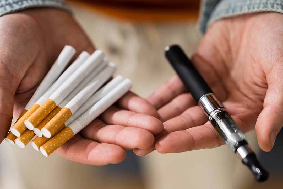 Hände halten Zigaretten und E-Zigaretten