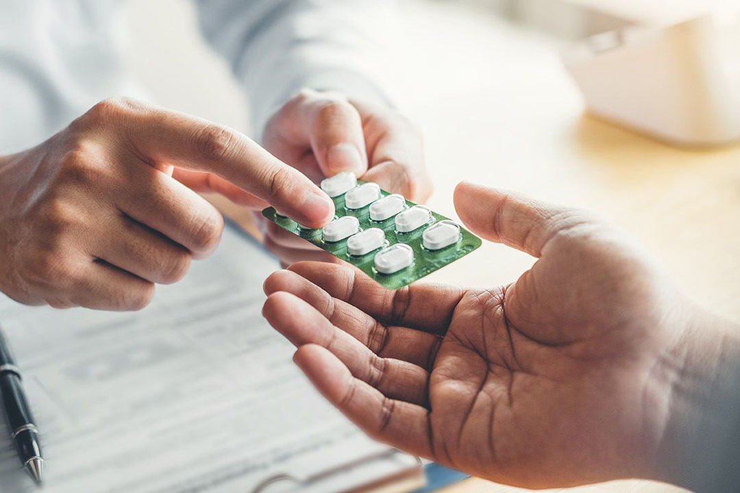 Nahaufnahme von deinem Arzt der einem Patienten ein Tablettenblister reicht
