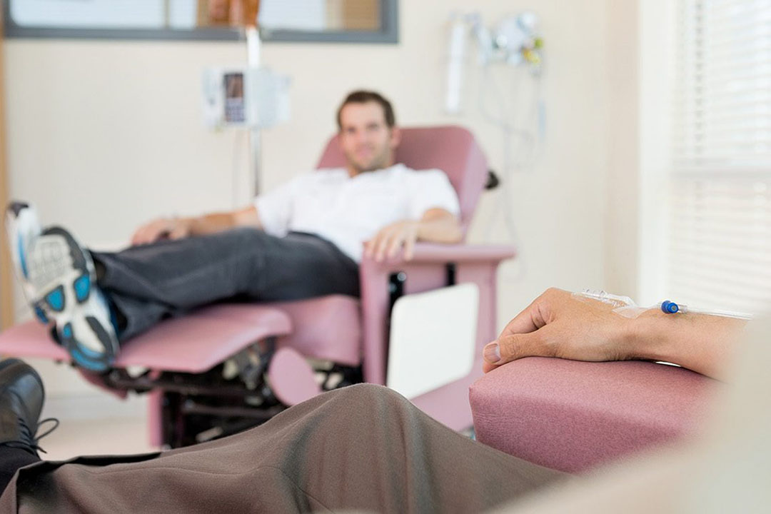 Ein Mann sitz auf einem Sessel und bekommt eine Infusion