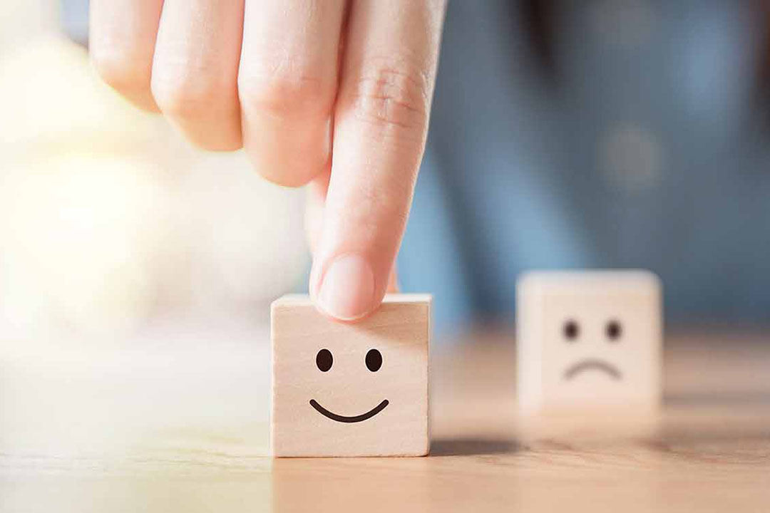 Nahaufnahme von einem positiven und einem negativer Smiley auf Holzwürfeln
