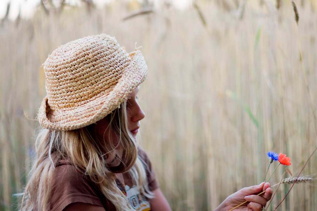 Eine junge Frau betrachtet Blumen im Kornfeld