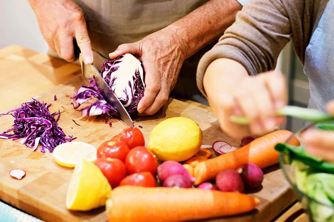 Ein Paar schneidet gemeinsam Gemüse klein