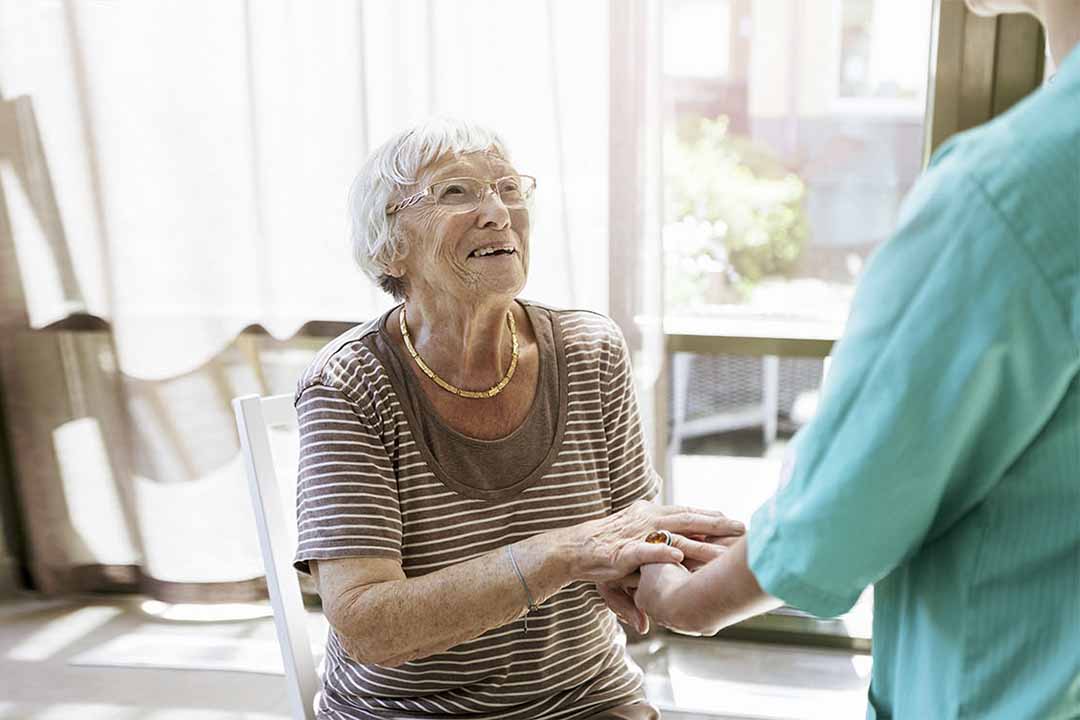 Ältere Frau umfasst die Hände Ihrer Pflegerin