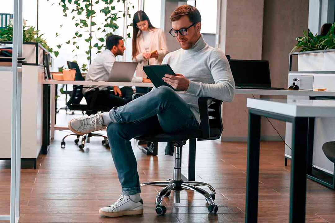 Ein Mann mit Tablet sitzt auf einem Bürostuhl
