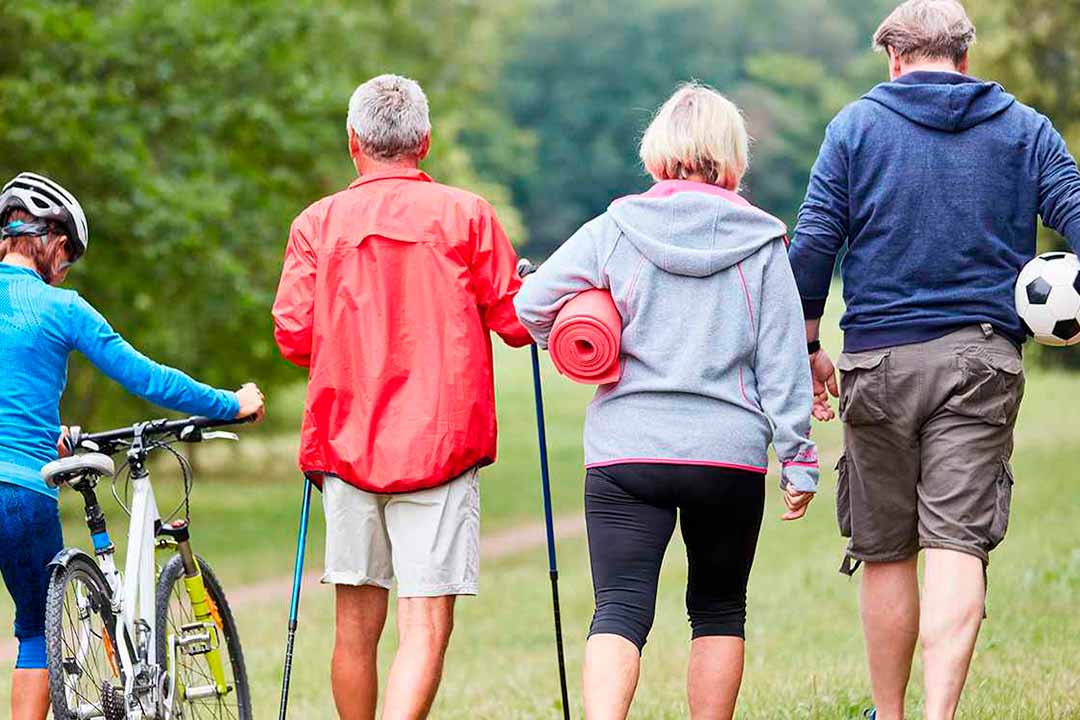 Vier sportliche Menschen mit Bike, Nordic-Walking Sticks, Jogamatte, Ball