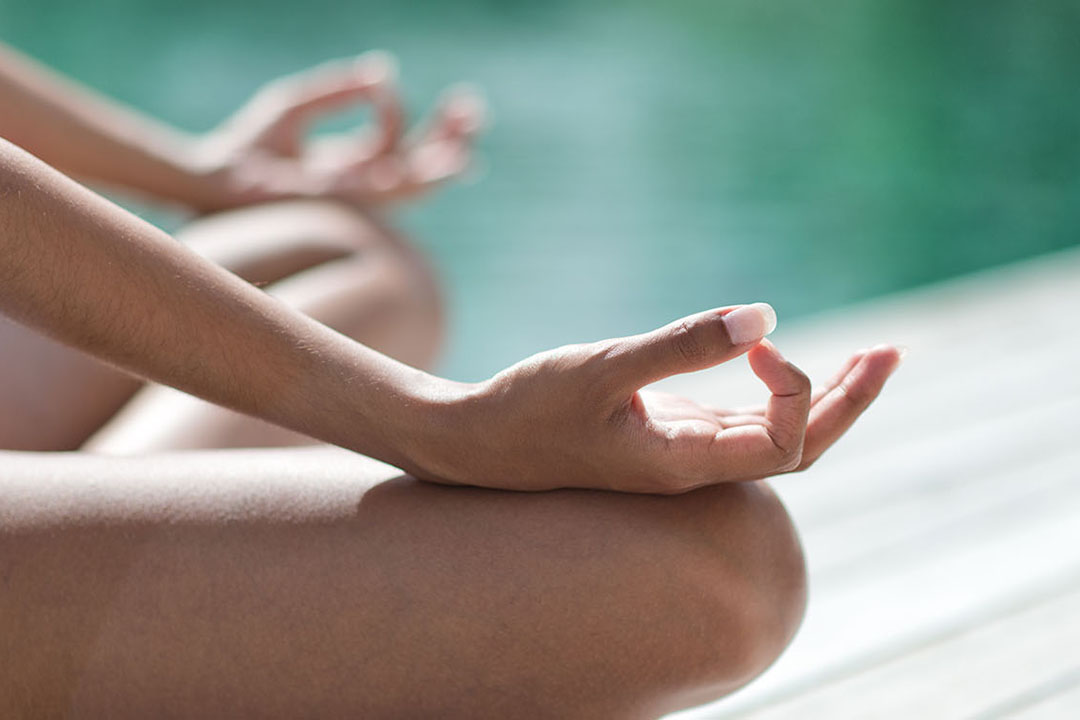 Yogaübung am See, eine Frau im Schneidersitz
