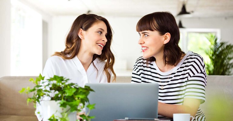 Zwei Frauen sitzen gemeinsam am Laptop