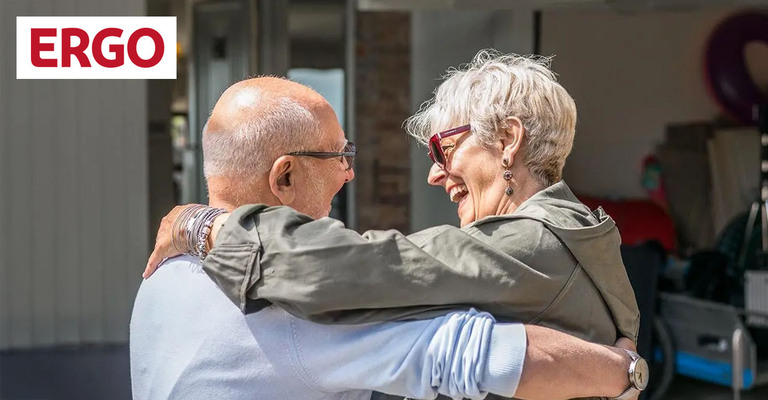 in älteres Paar umarmt sich und lächelt sich an. Bild mit  einem Logo der ERGO in der oberen linken Ecke.