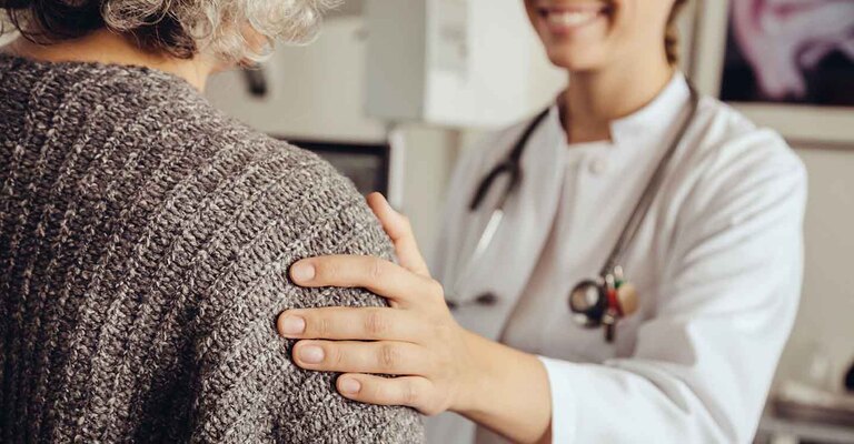 Ärztin berührt eine Patientin an der Schulter