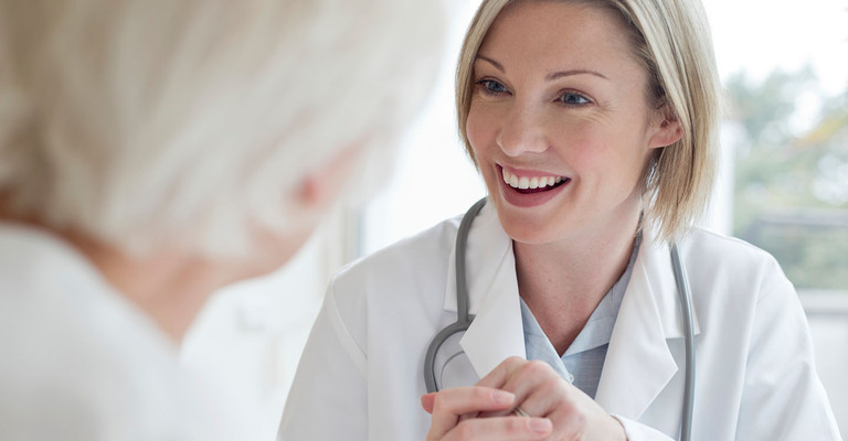 Eine Ärztin hält die Hand ihrer Patientin