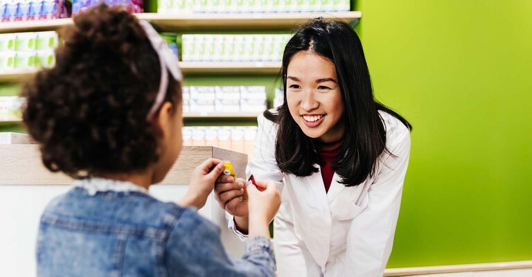 Apothekerin gibt einem Kind ein Bonbon