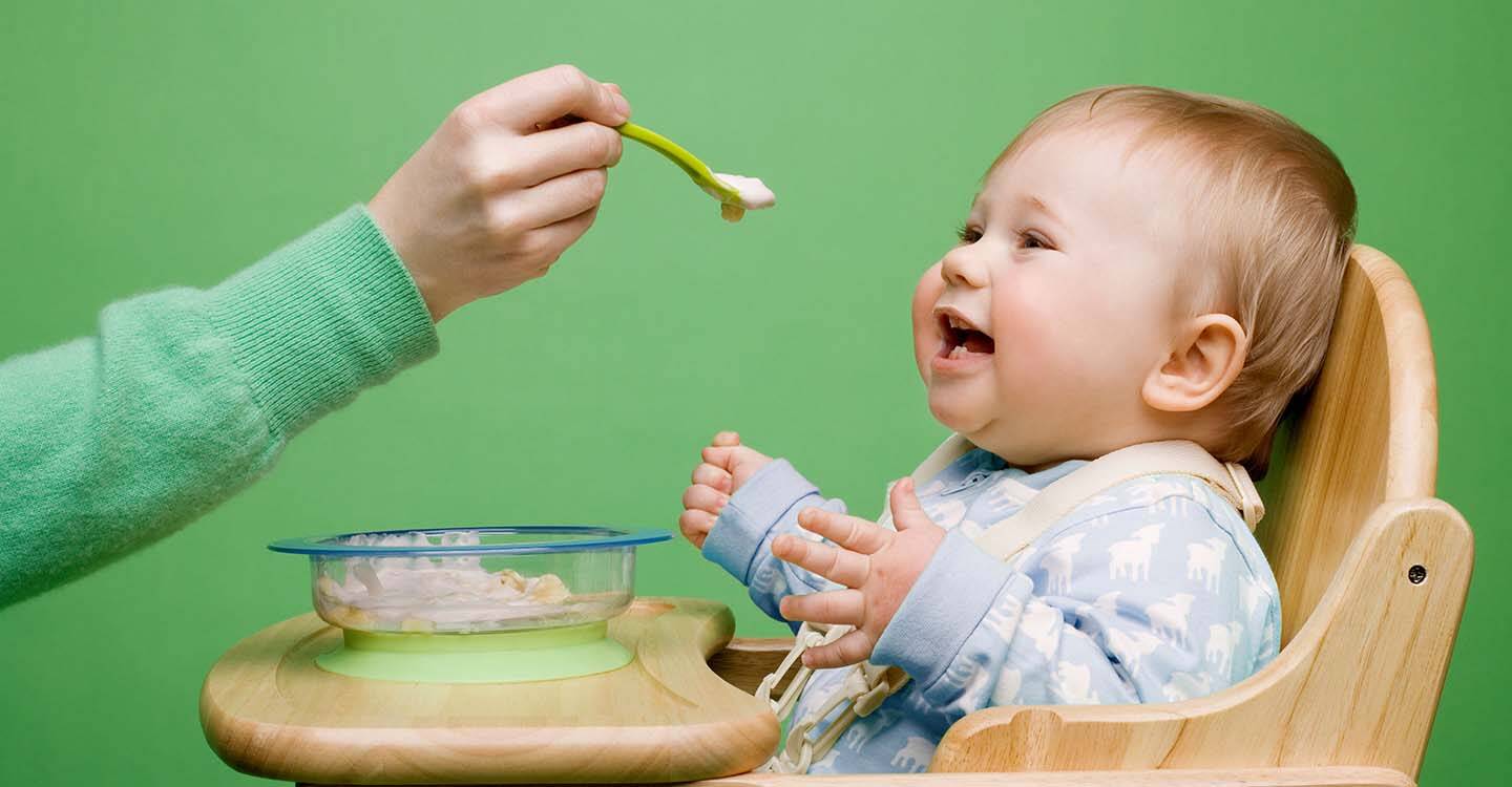 Baby im Hochstuhl wird gefüttert