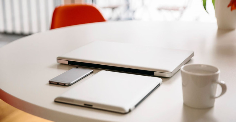 Ein Laptop, Tablet, Smartphone liegen auf einem Tisch