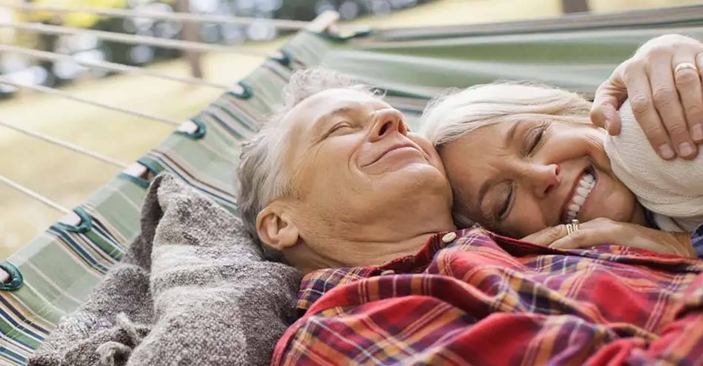 Ein älteres Paar liegt in einer Hängematte