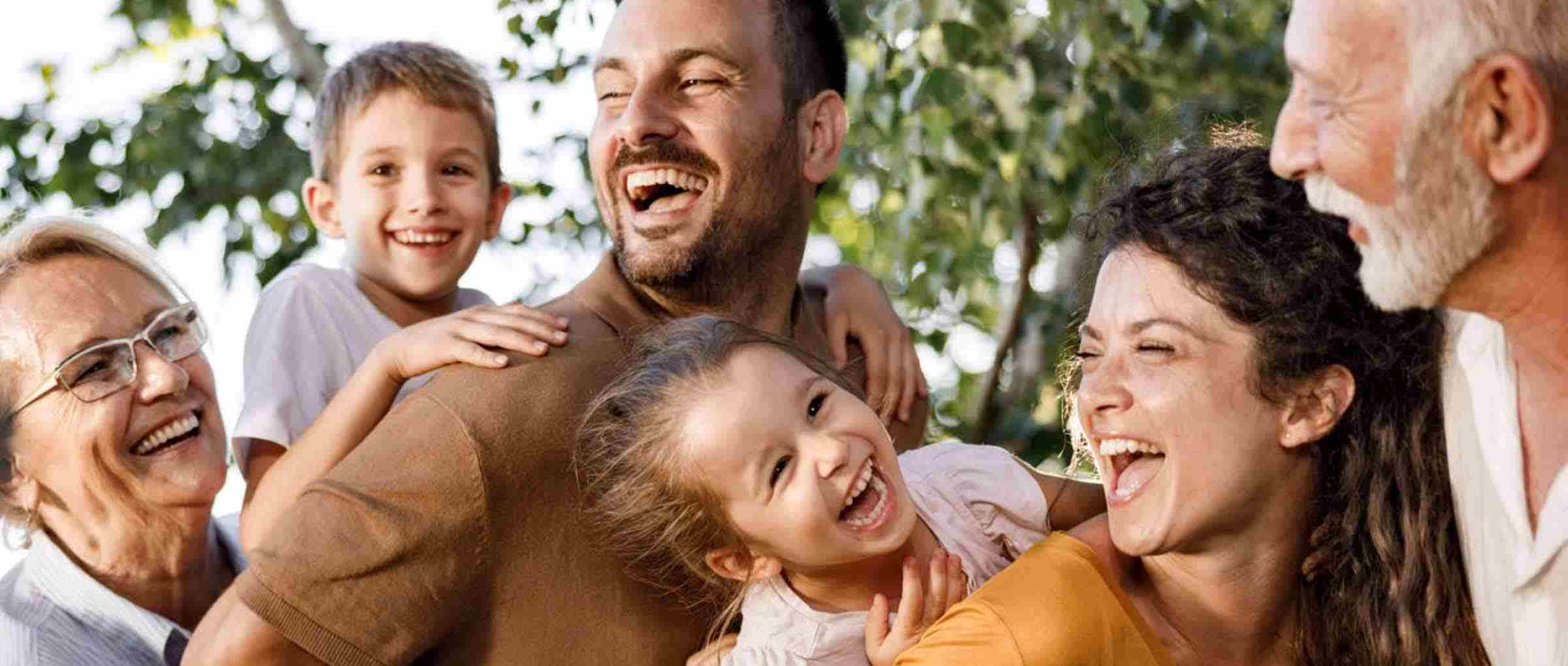 Eine Familie mit 6 lachenden Personen vor einem Baum