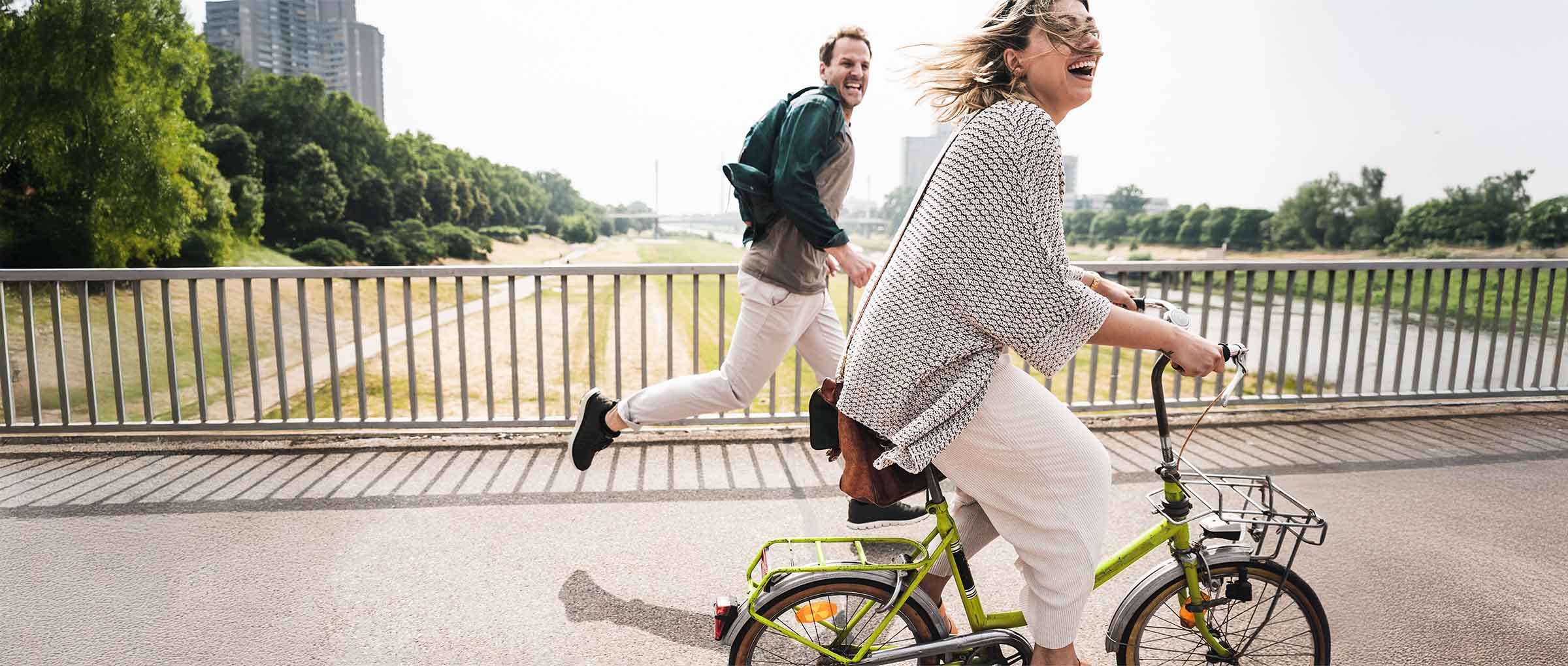 Eine Frau auf einem Rad, im Hintergrund ein rennender Mann