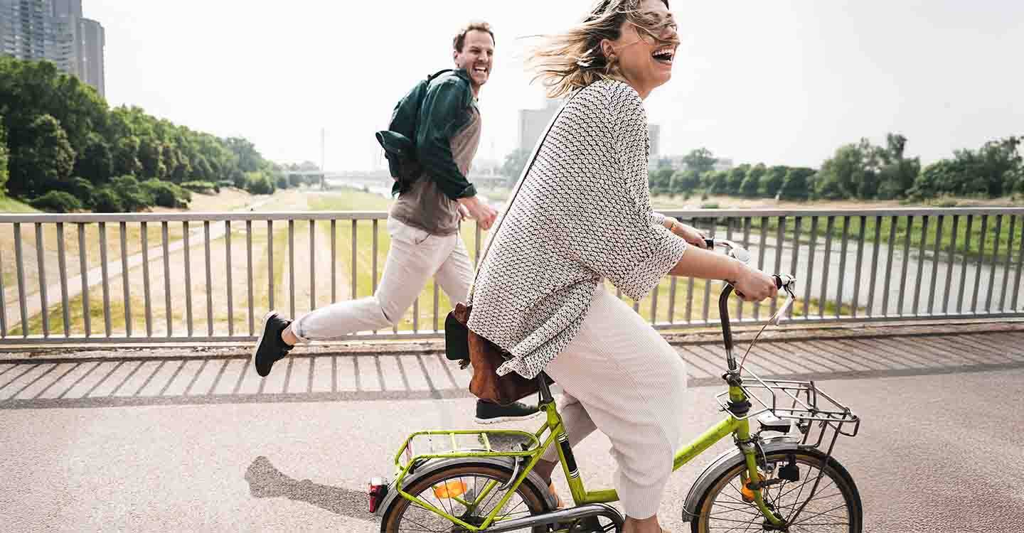 Eine Frau auf einem Rad im Hintergrund ein rennender Mann