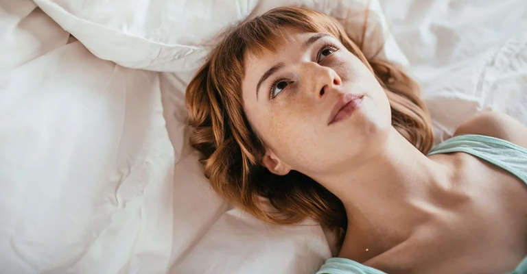 Eine Frau liegt im Bett und schaut zur Decke