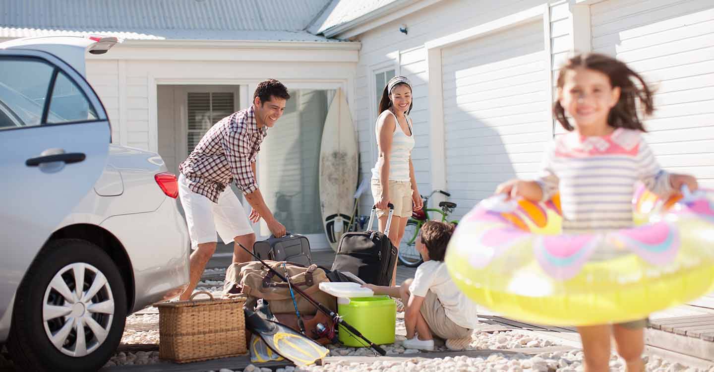 Familie, die gerade am Urlaubsort angekommen ist, entlädt das Reisegepäck