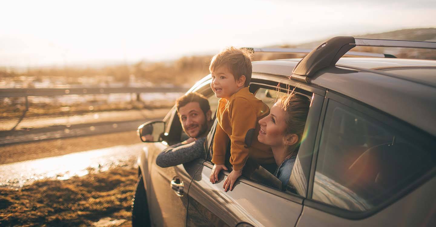 Familie parkt mit Auto am Strand und schaut in die Ferne