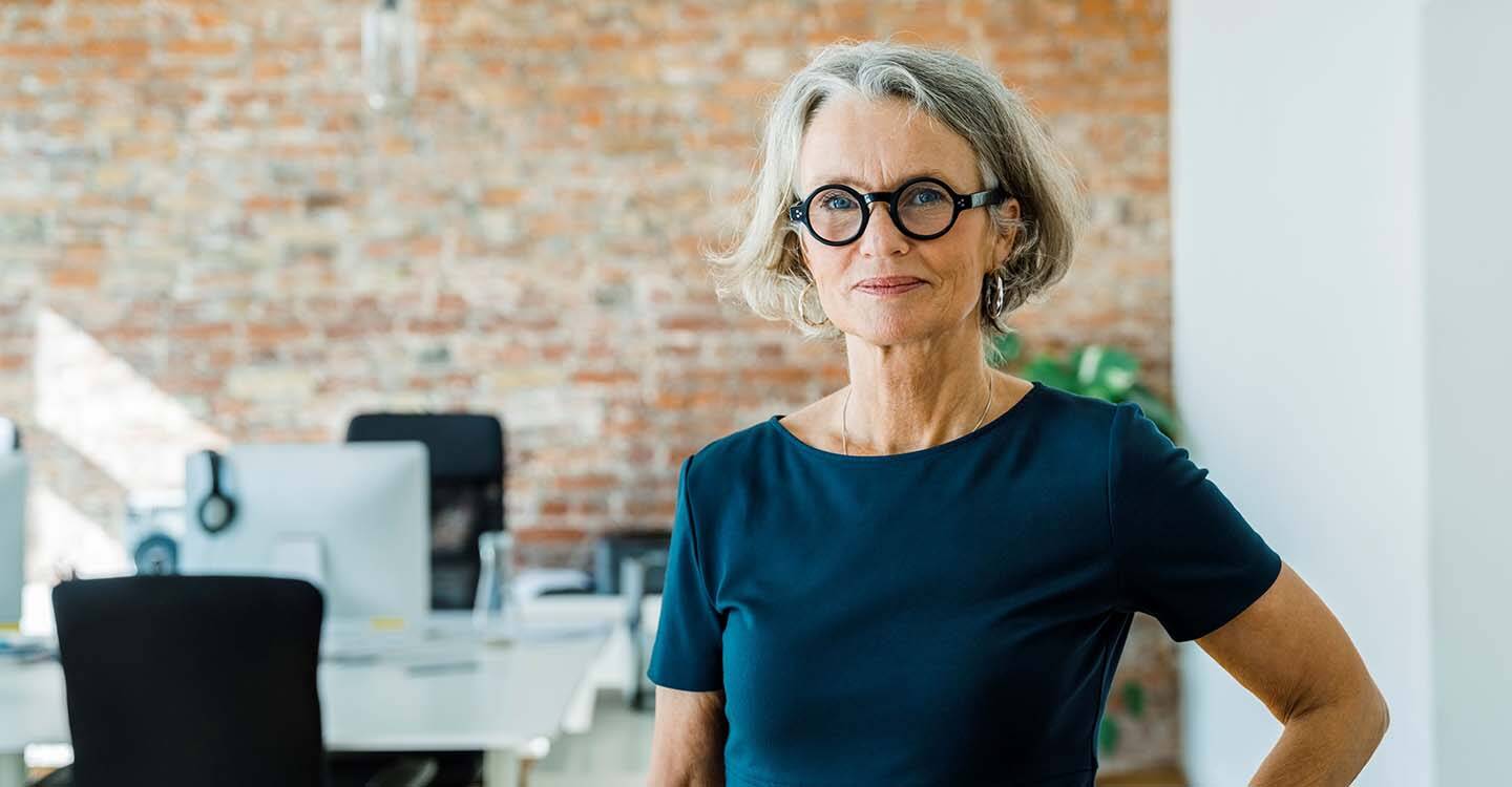 Frau mit Brille steht im Büro