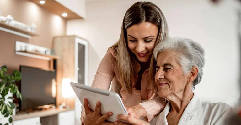 Frau zeigt älteren Frau ein Tablet