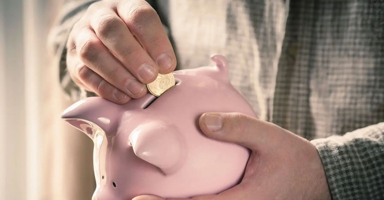 Geldstück wird in ein Sparschwein gesteckt