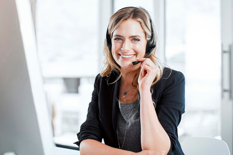 Frau lächelt dich direkt an und hat dabei Headset auf.