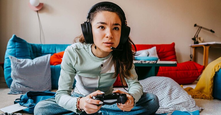 Junge Frau mit Kopfhörern und Controller in der Hand