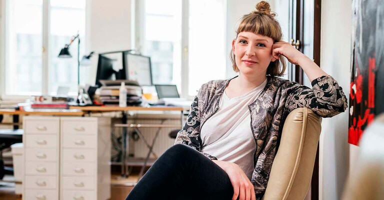 Junge Frau auf einem Stuhl schaut in die Kamera